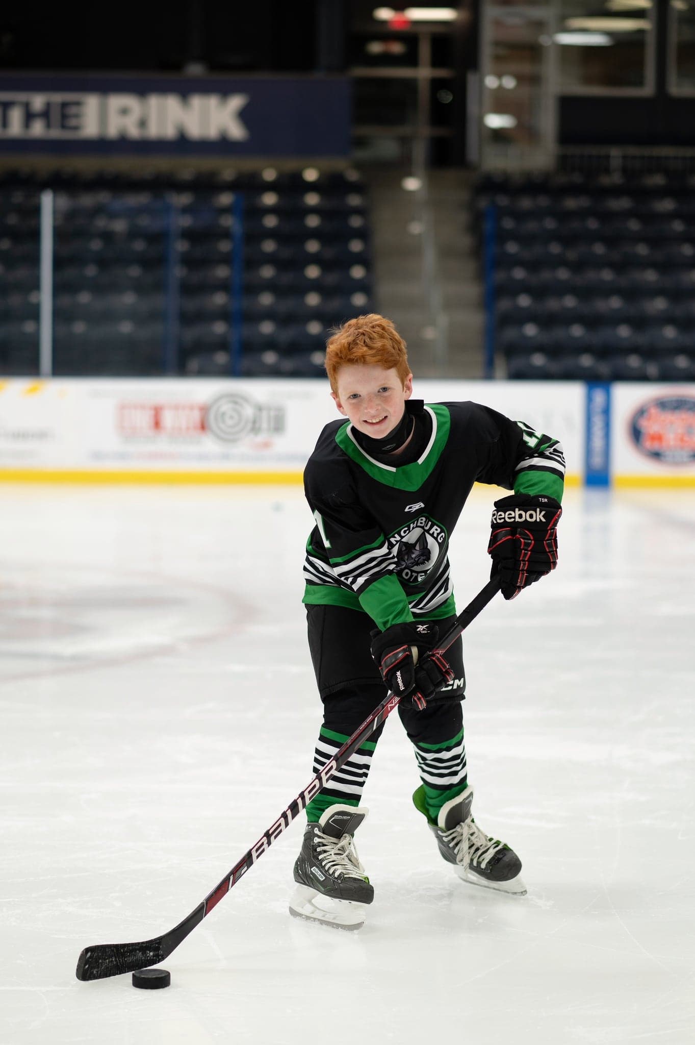 Smiling Coyotes player with his stick on the puck at center ice
