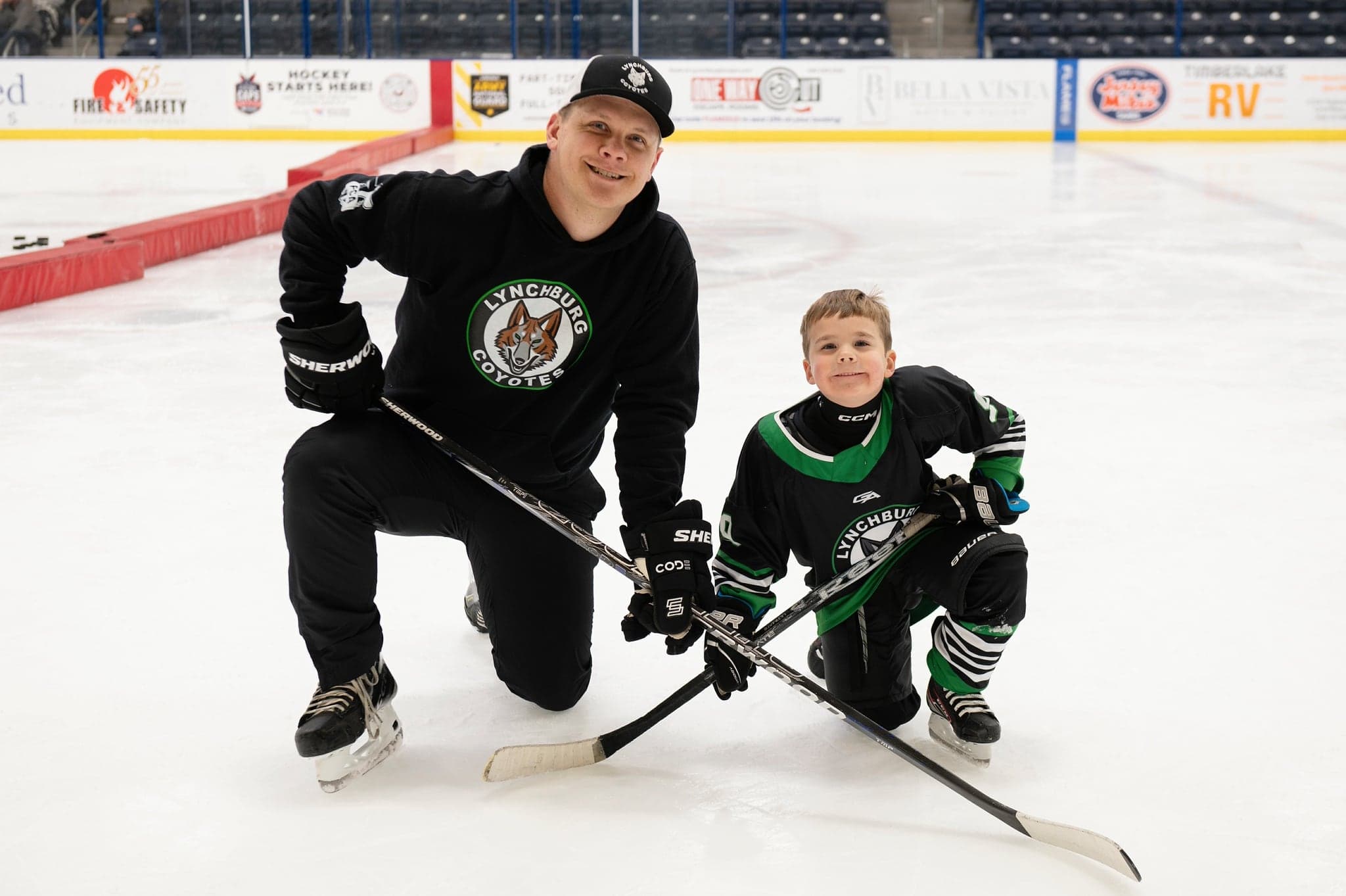 Coach kneeling beside a young Coyotes player on the ice