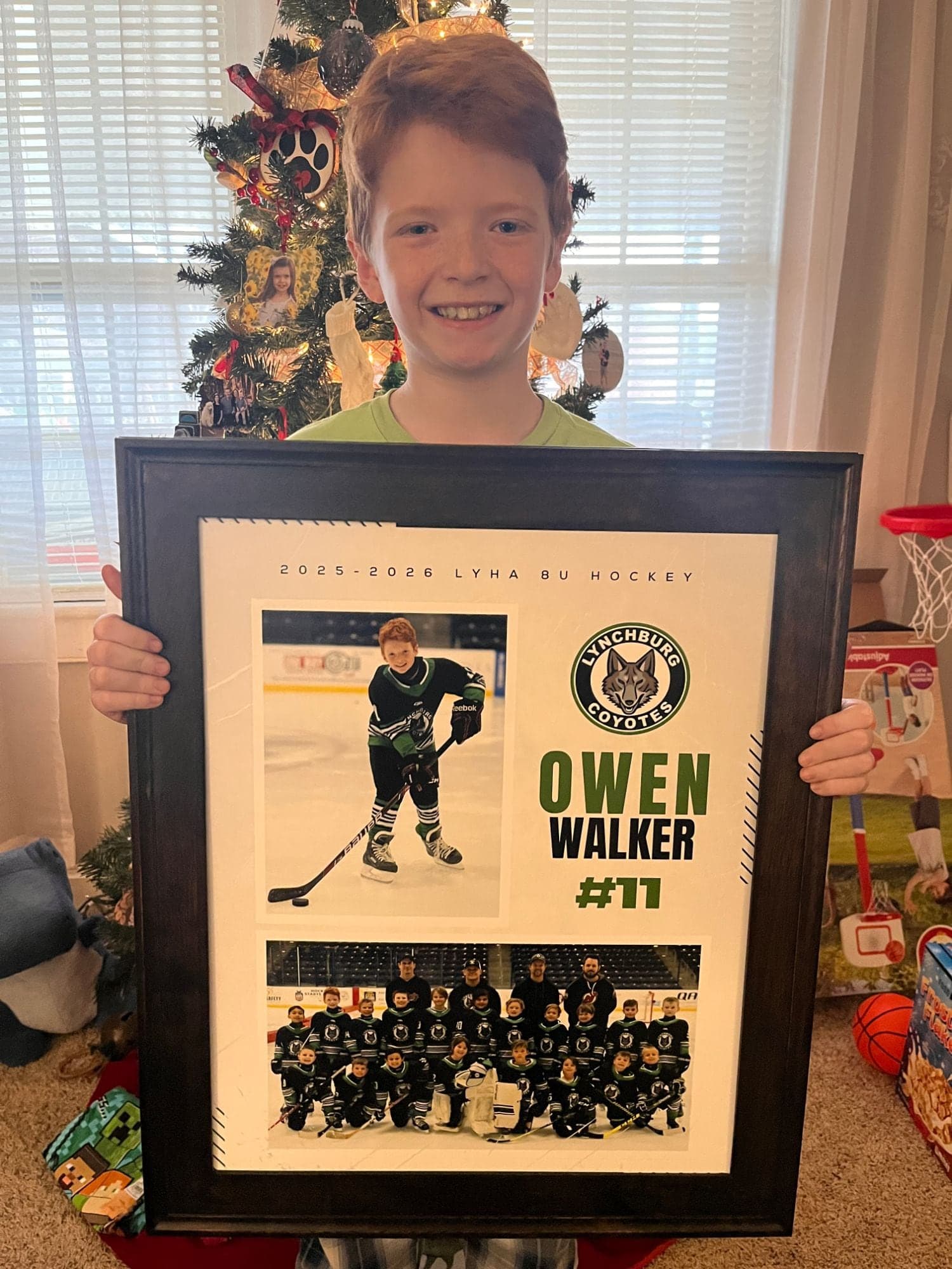 Owen holding his 16x20 mounted print, with his player portrait, his name and number, and the team photo